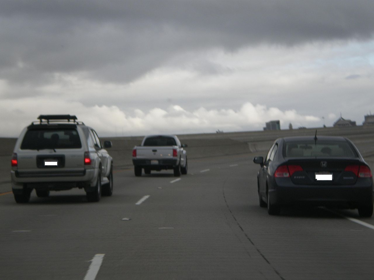 Multi-lane Interstate 880 cutting through Oakland with buildings and hills in the distance